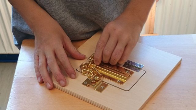 Das Foto zeigt zwei Hände, die versuchen, ein Türschloss zu öffnen.