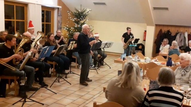 Das Foto zeigt die Blasmusikanten auf der linken Seite, in der Mitte des Fotos singt Adolf Heckmann.