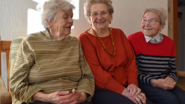Drei Frauen sitzen auf einer Bank.